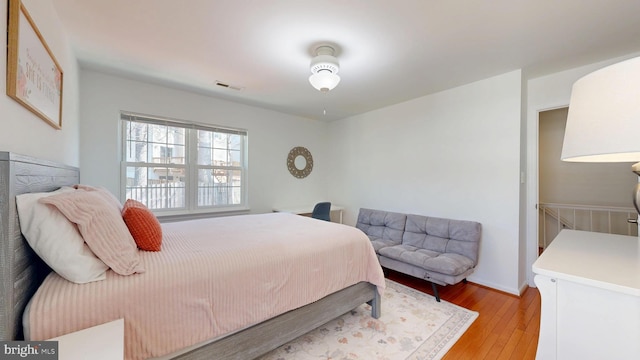 bedroom with light wood-style floors and visible vents