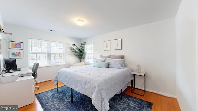 bedroom with visible vents, wood finished floors, and baseboards