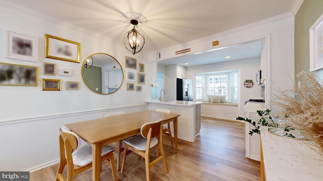 dining space with light wood finished floors, baseboards, an inviting chandelier, and ornamental molding