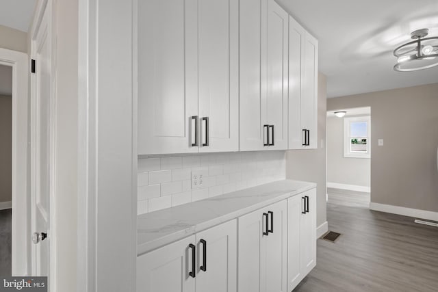 interior space with visible vents, backsplash, baseboards, and wood finished floors