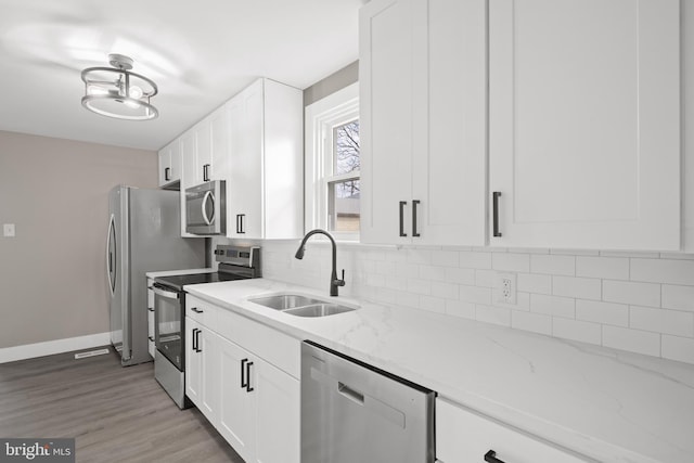 kitchen with tasteful backsplash, white cabinets, stainless steel appliances, and a sink