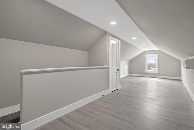 bonus room featuring baseboards, vaulted ceiling, recessed lighting, wood finished floors, and a wall mounted AC