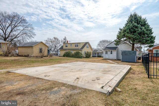 view of yard with a shed, concrete driveway, an outdoor structure, and fence