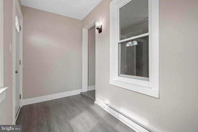 interior space with baseboard heating, baseboards, and wood finished floors