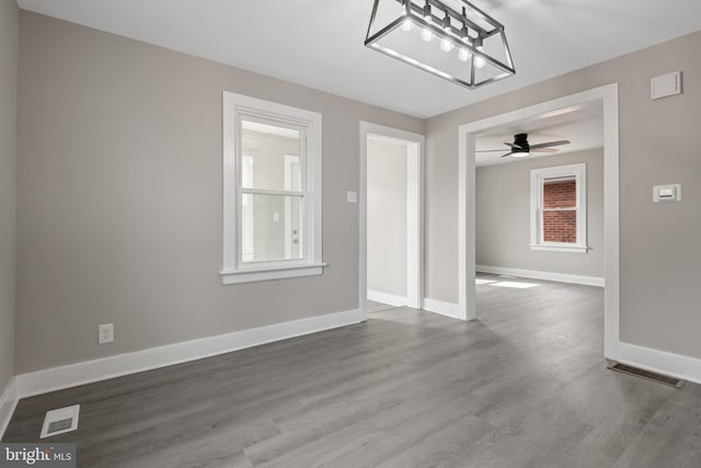 unfurnished dining area with dark wood-type flooring, baseboards, and visible vents