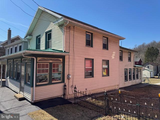 view of side of property with fence and a sunroom