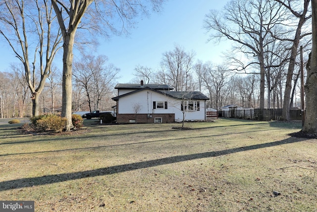 view of side of home with fence and a lawn