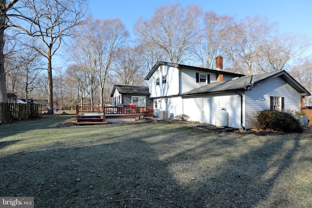 exterior space featuring a deck, central AC, fence, a yard, and a chimney