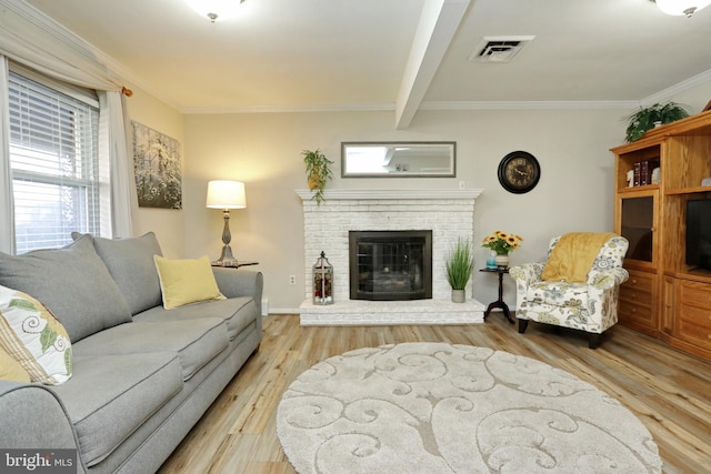 living area featuring visible vents, beamed ceiling, ornamental molding, wood finished floors, and a brick fireplace