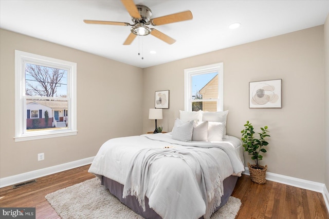 bedroom featuring wood finished floors, multiple windows, baseboards, and visible vents