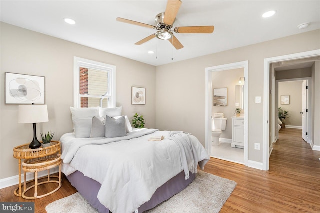 bedroom featuring baseboards, recessed lighting, light wood-style flooring, ensuite bathroom, and a ceiling fan