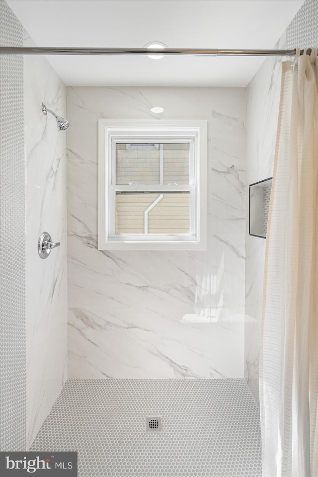 bathroom featuring a marble finish shower