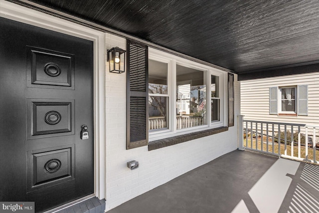 property entrance featuring brick siding and covered porch