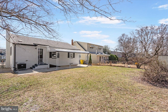 rear view of house featuring fence, a yard, central AC unit, a chimney, and a patio area