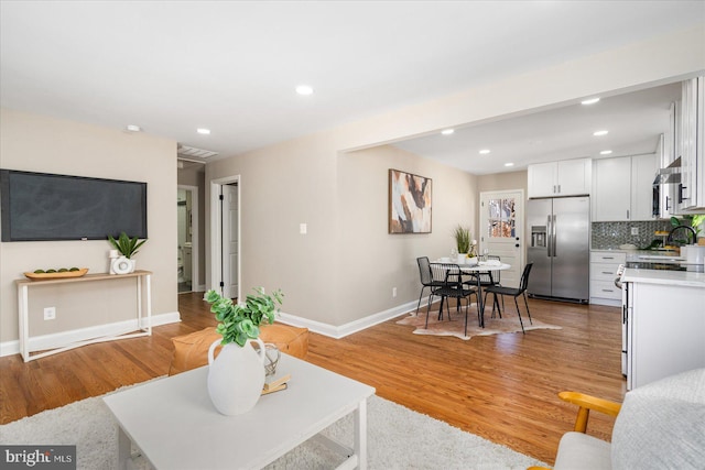 living room featuring light wood-style flooring, recessed lighting, and baseboards