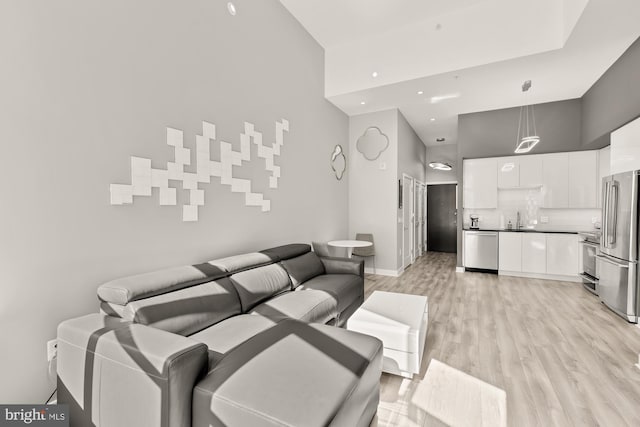 living room featuring light wood-style floors, baseboards, and a towering ceiling