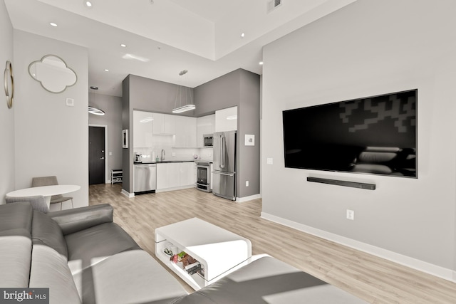 living room with visible vents, light wood-style flooring, recessed lighting, baseboards, and a towering ceiling