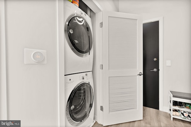 washroom with stacked washer and clothes dryer and light wood finished floors