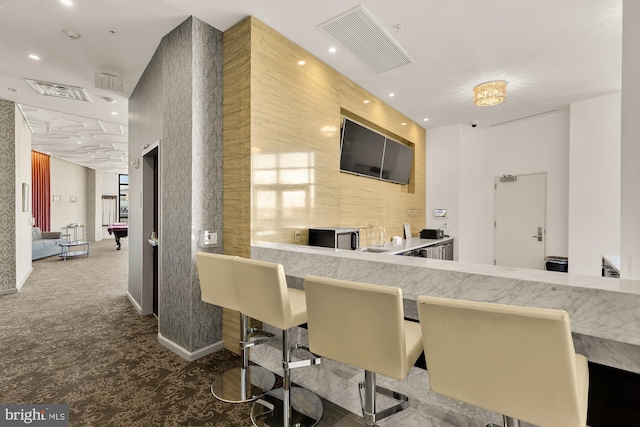 kitchen featuring carpet flooring, recessed lighting, a breakfast bar area, and visible vents