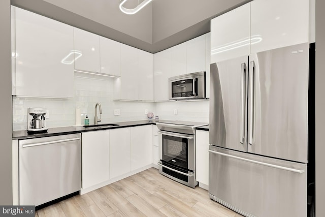 kitchen featuring dark countertops, appliances with stainless steel finishes, white cabinetry, and a sink