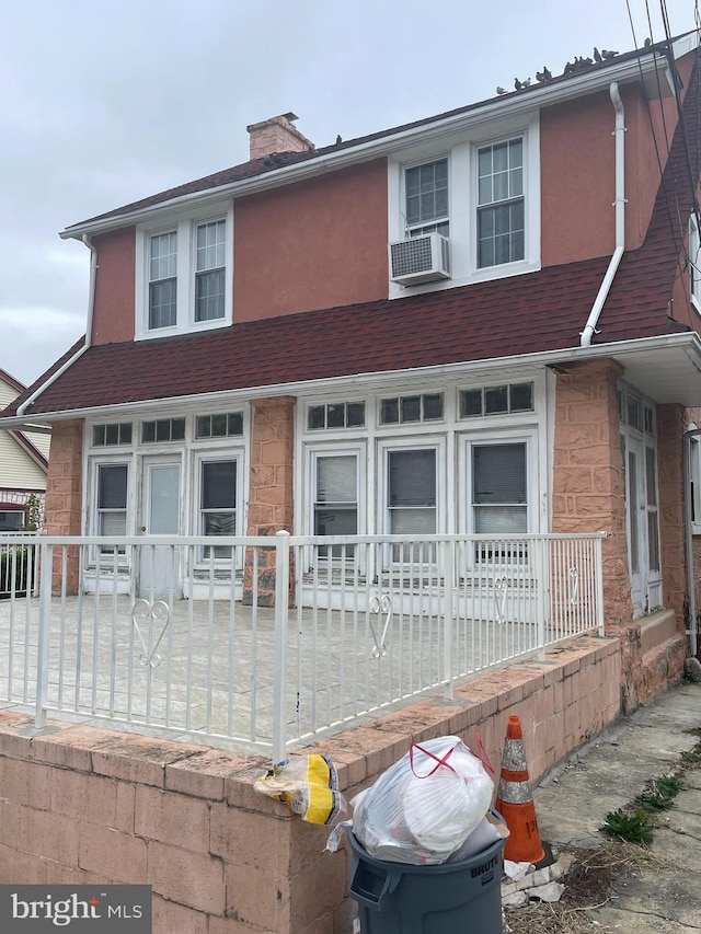 27 Wellington Rd, Upper Darby, PA 19082 - view of front facade with covered porch, stone siding, a chimney, cooling unit, and stucco siding