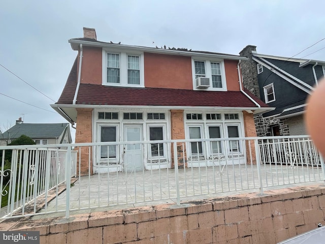 27 Wellington Rd, Upper Darby, PA 19082 - view of front of house with a chimney, cooling unit, fence, and stucco siding