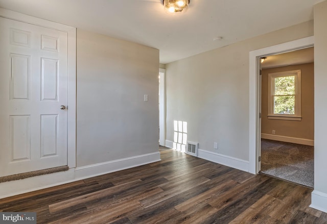 empty room with visible vents, baseboards, and dark wood-style flooring