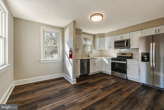 kitchen with tasteful backsplash, appliances with stainless steel finishes, dark wood finished floors, and light countertops