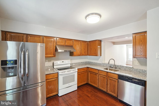 kitchen featuring brown cabinetry, dark wood-style flooring, a sink, stainless steel appliances, and under cabinet range hood