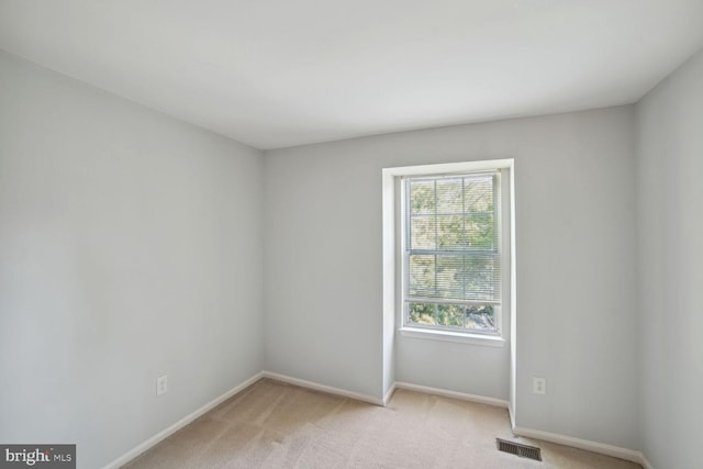 empty room featuring baseboards, visible vents, and light carpet