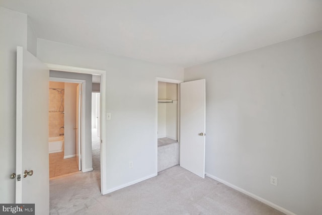 unfurnished bedroom featuring baseboards, a closet, and light carpet