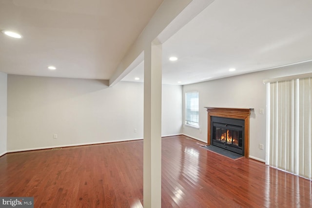 unfurnished living room with a fireplace with flush hearth, recessed lighting, baseboards, and wood finished floors