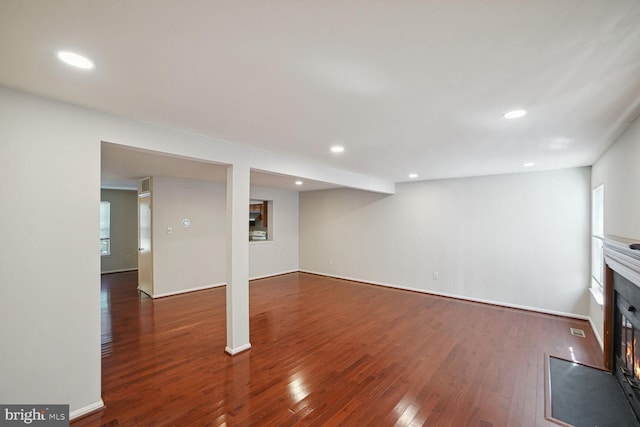 below grade area featuring a glass covered fireplace, recessed lighting, visible vents, and hardwood / wood-style floors