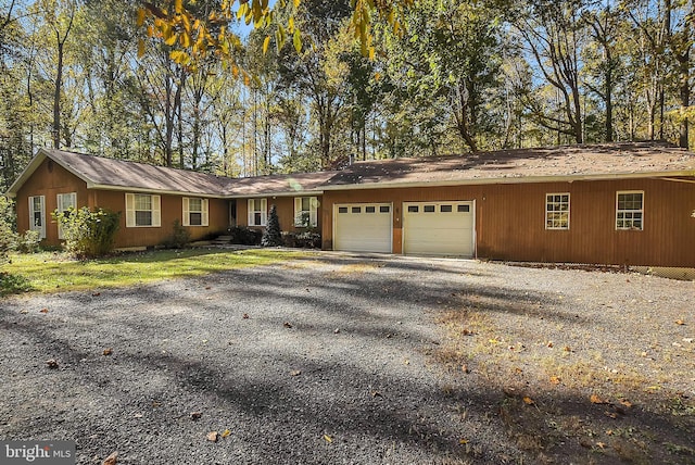 single story home featuring an attached garage and gravel driveway