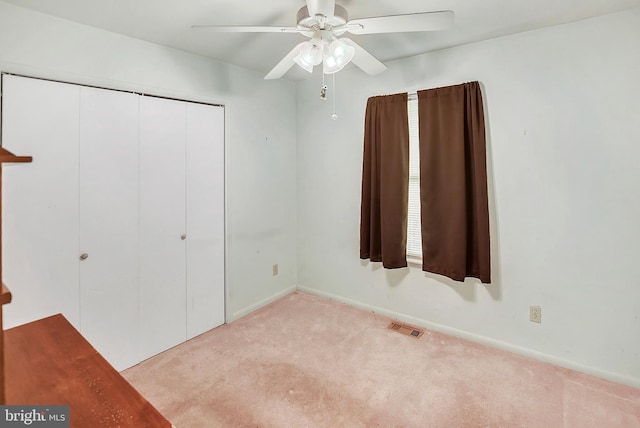 unfurnished bedroom with visible vents, a closet, carpet flooring, baseboards, and ceiling fan