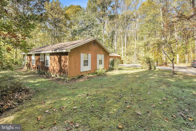 view of home's exterior featuring a lawn and a forest view