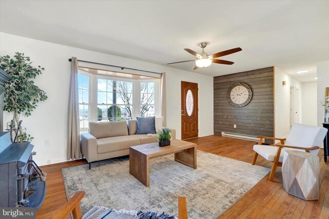 living room featuring ceiling fan, wood finished floors, baseboards, and a baseboard radiator