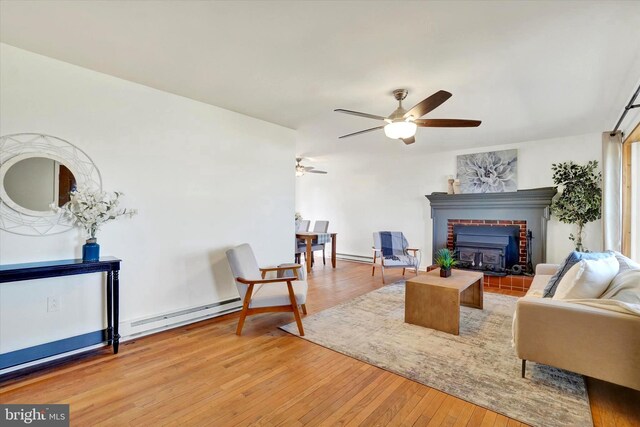 living area with light wood-type flooring, baseboard heating, and a ceiling fan