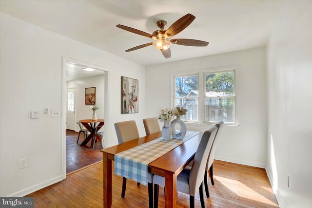 dining space featuring light wood-style flooring, a ceiling fan, and baseboards