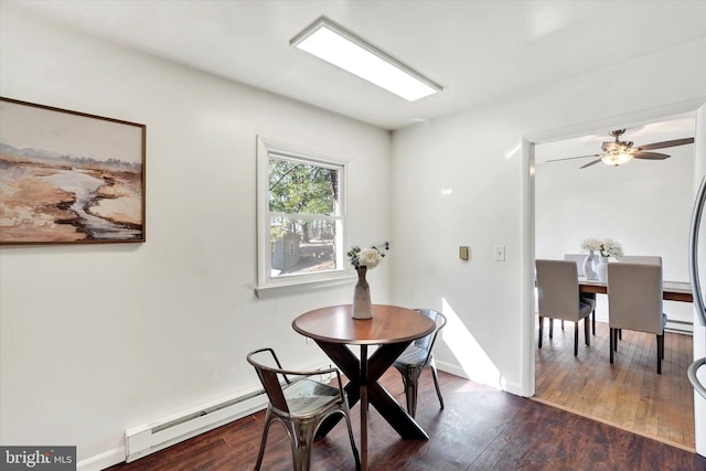 dining space with a baseboard heating unit, baseboards, and wood finished floors