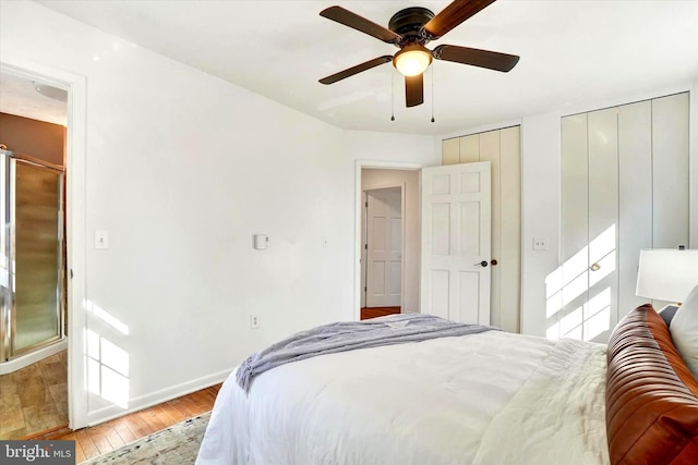 bedroom featuring two closets, a ceiling fan, baseboards, and hardwood / wood-style flooring