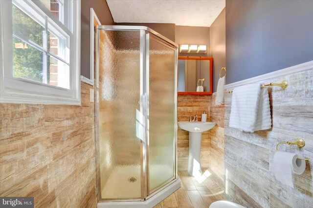 bathroom featuring a shower stall, tile walls, and a wainscoted wall