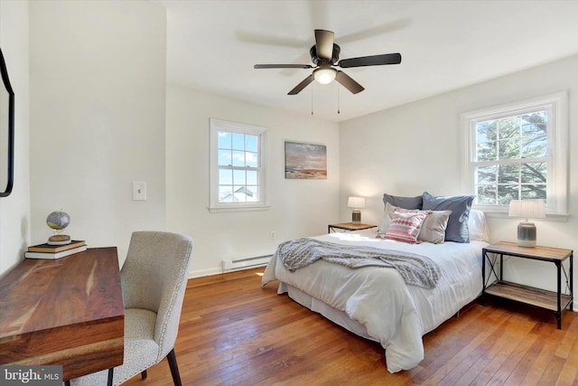 bedroom featuring a baseboard heating unit, wood-type flooring, and a ceiling fan