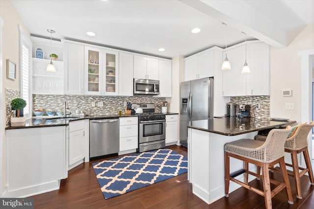 kitchen with dark wood-style floors, appliances with stainless steel finishes, white cabinetry, and a peninsula