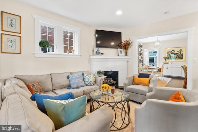 living room with a brick fireplace, recessed lighting, and a chandelier