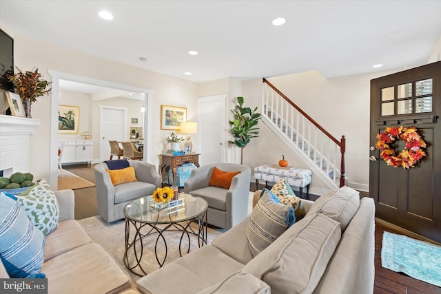 living area featuring stairs, a brick fireplace, recessed lighting, and wood finished floors