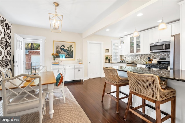 kitchen with dark wood-style floors, a sink, decorative backsplash, appliances with stainless steel finishes, and white cabinetry