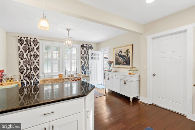 kitchen featuring a notable chandelier, decorative light fixtures, white cabinetry, dark stone counters, and dark wood-style flooring