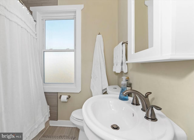 full bathroom featuring curtained shower, toilet, baseboards, and a sink