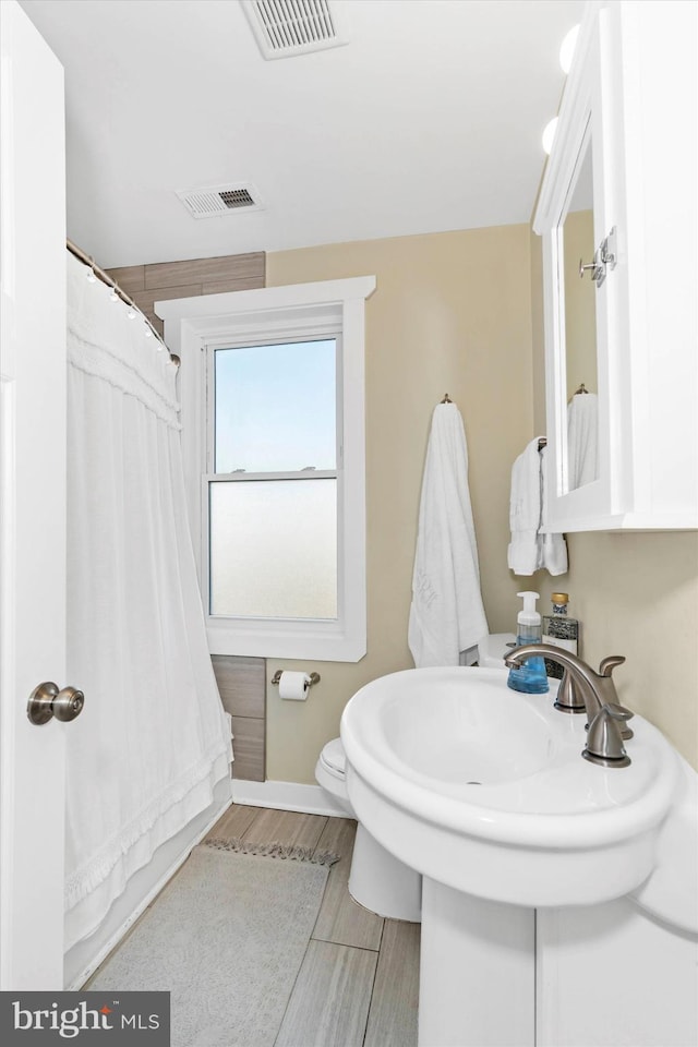 bathroom with toilet, baseboards, visible vents, and wood tiled floor